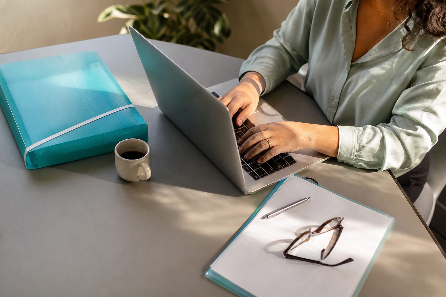 Mesa de escritório vista de cima com notebook, pastas de arquivo, prancheta e xícara de café